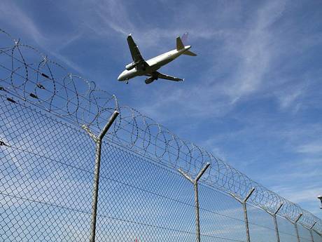 Un avion est flying haut de la chain link clôture avec fil de rasoir.